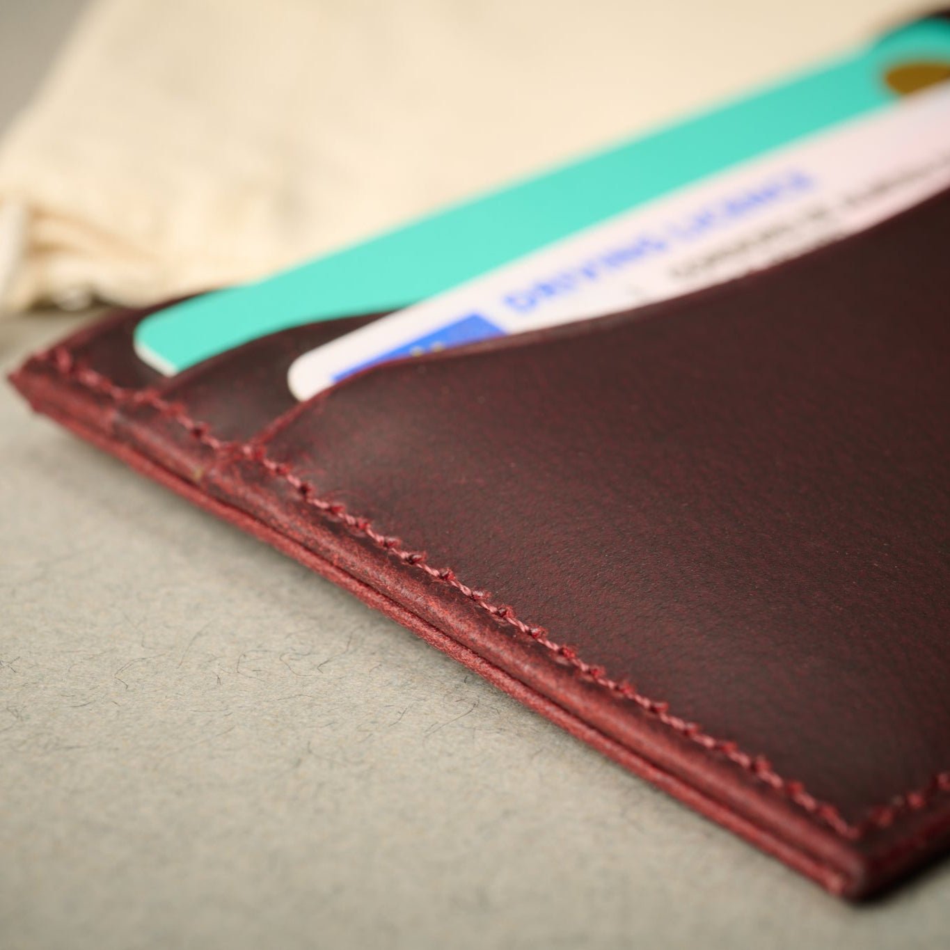 Close up of the burgundy full grain leather card case with cards. 5 RFID Blocking card slots. Watch And Strap.