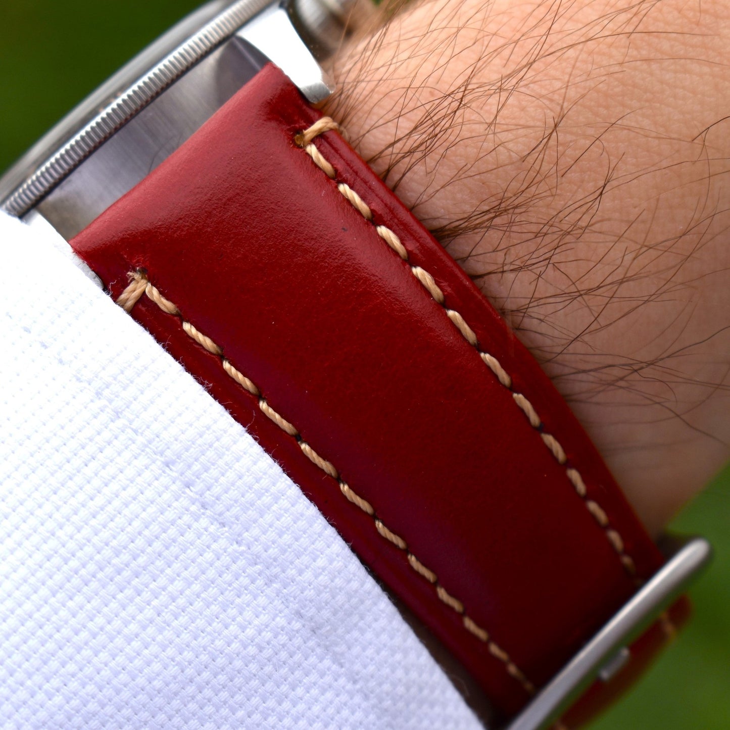 Wrist shot of the Oslo blood red full grain leather leather apple watch strap. Placed on a males wrist with a white sleeve.