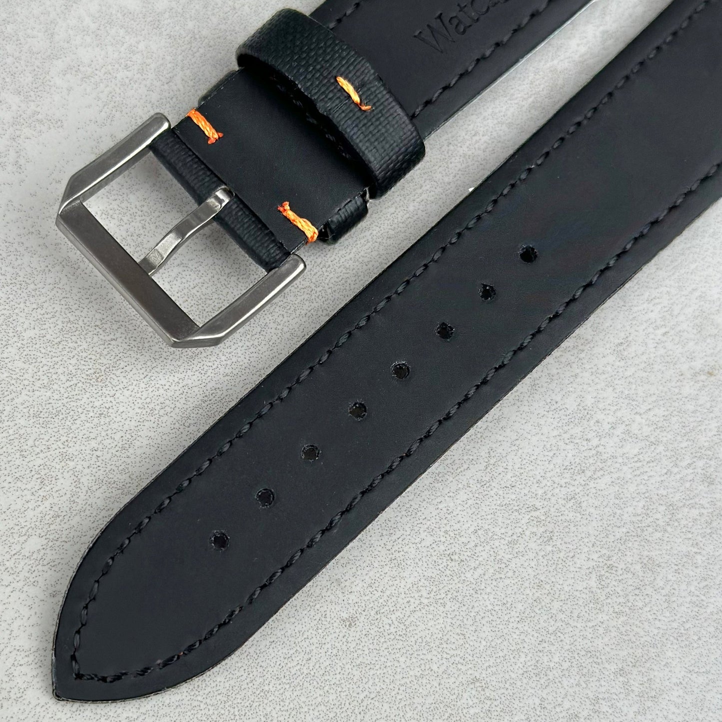 Underside of the brushed 316L stainless steel buckle on the Bermuda jet black sail cloth watch strap with orange stitching.