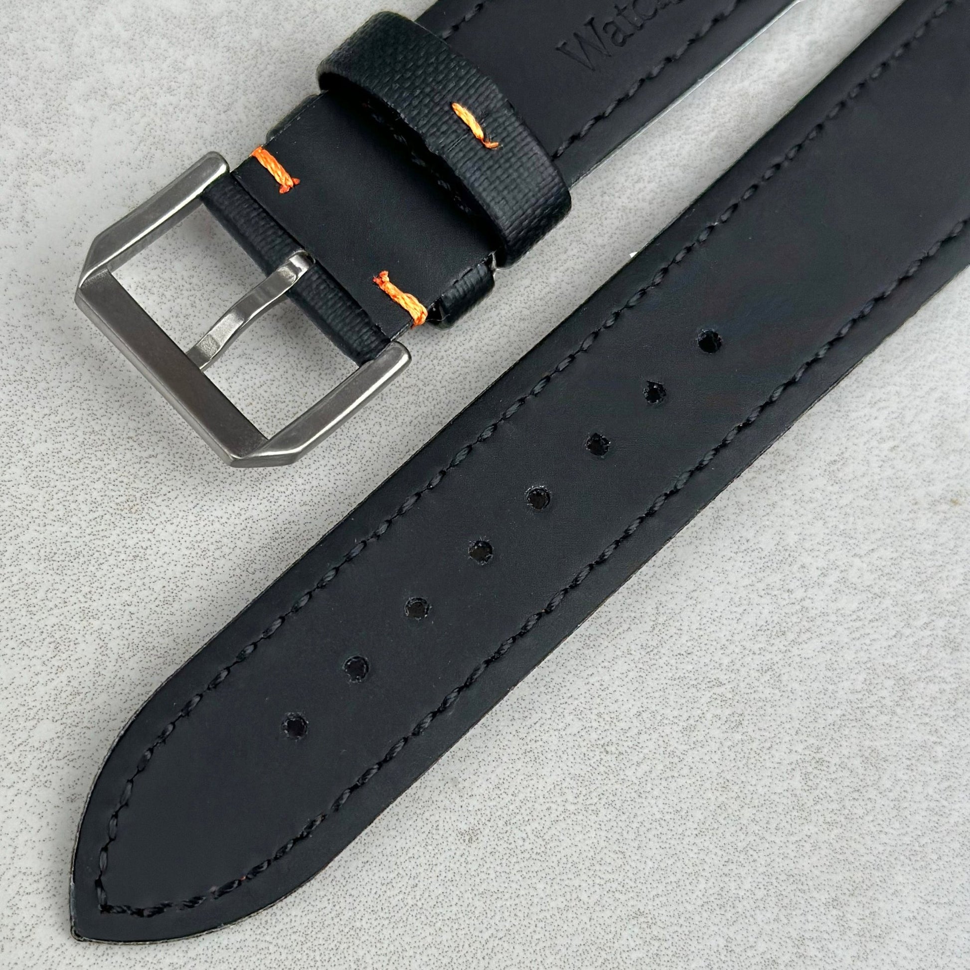 Underside of the brushed 316L stainless steel buckle on the Bermuda jet black sail cloth watch strap with orange stitching.