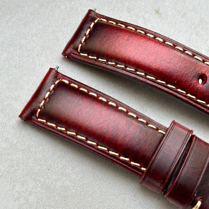 Close up of the top of the Berlin burgundy full grain leather watch strap. Burgundy leather, contrast ivory stitching.