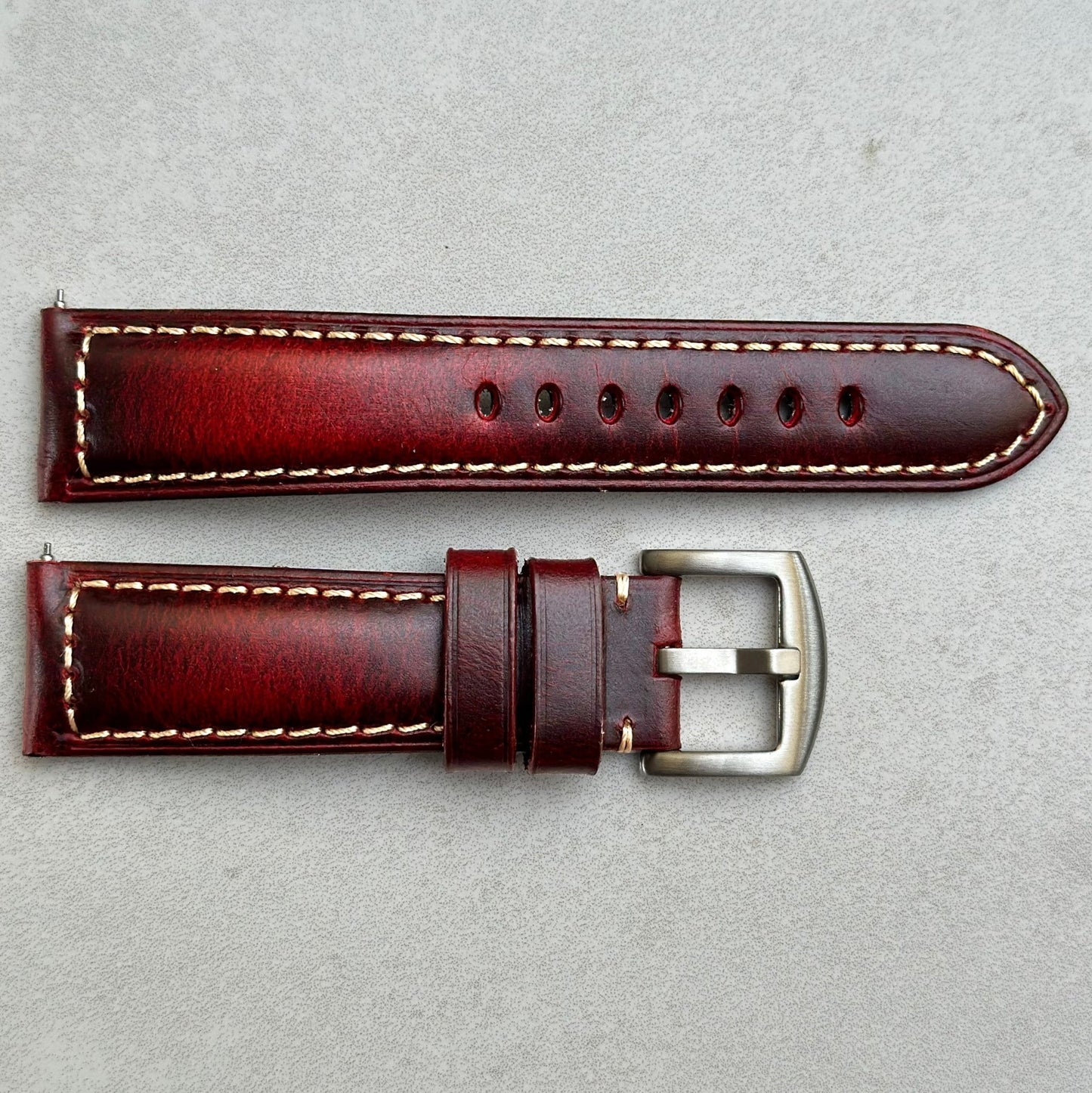 Birds eye view shot of the Berlin burgundy full grain leather watch strap. Placed on a Grey background.