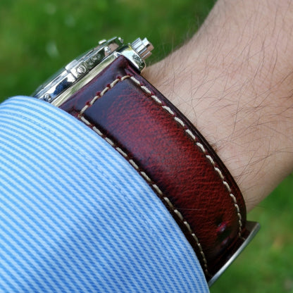 Wrist shot of the Berlin burgundy leather watch strap. Contrast ivory stitching.