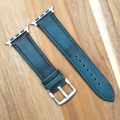 Milan blue vegetable tanned leather apple watch strap. Fitted with silver hardware and silver buckle. Placed on a wood background.