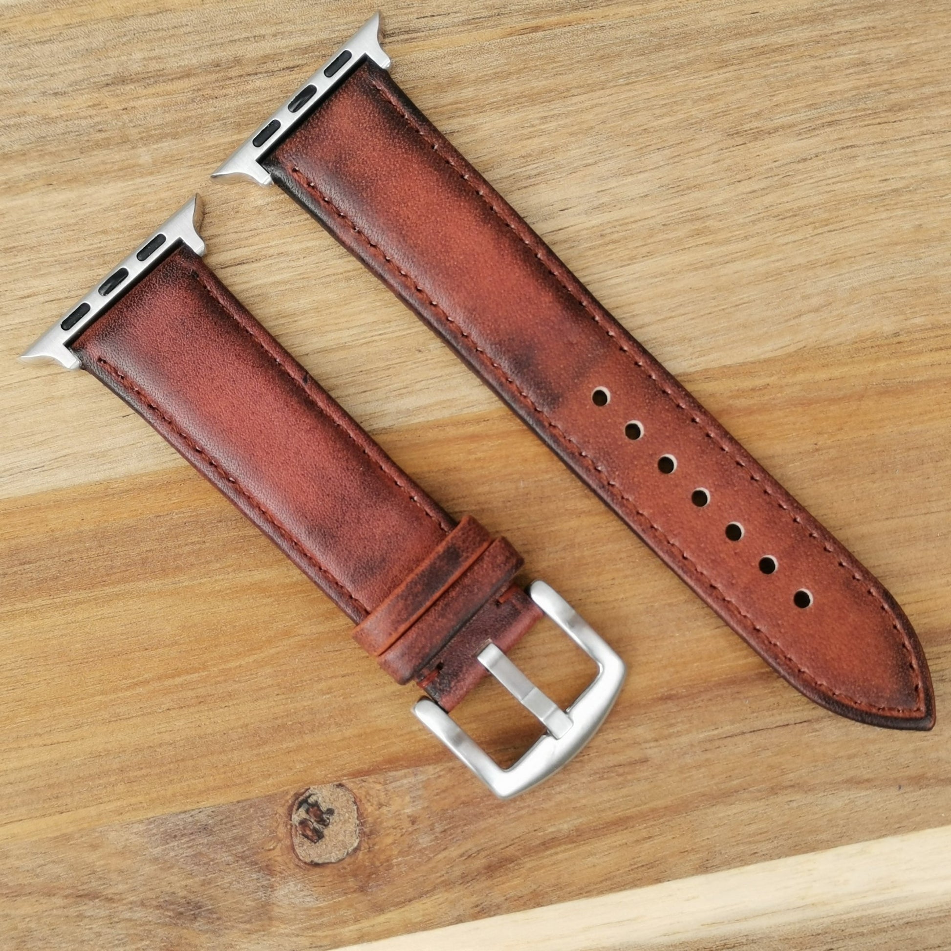 Milan brown vegetable tanned leather apple watch strap. Placed on a wood background under natural lighting.