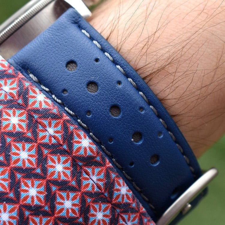 Le Mans blue and grey full grain leather racing watch strap. Mans sleeve and grass background.