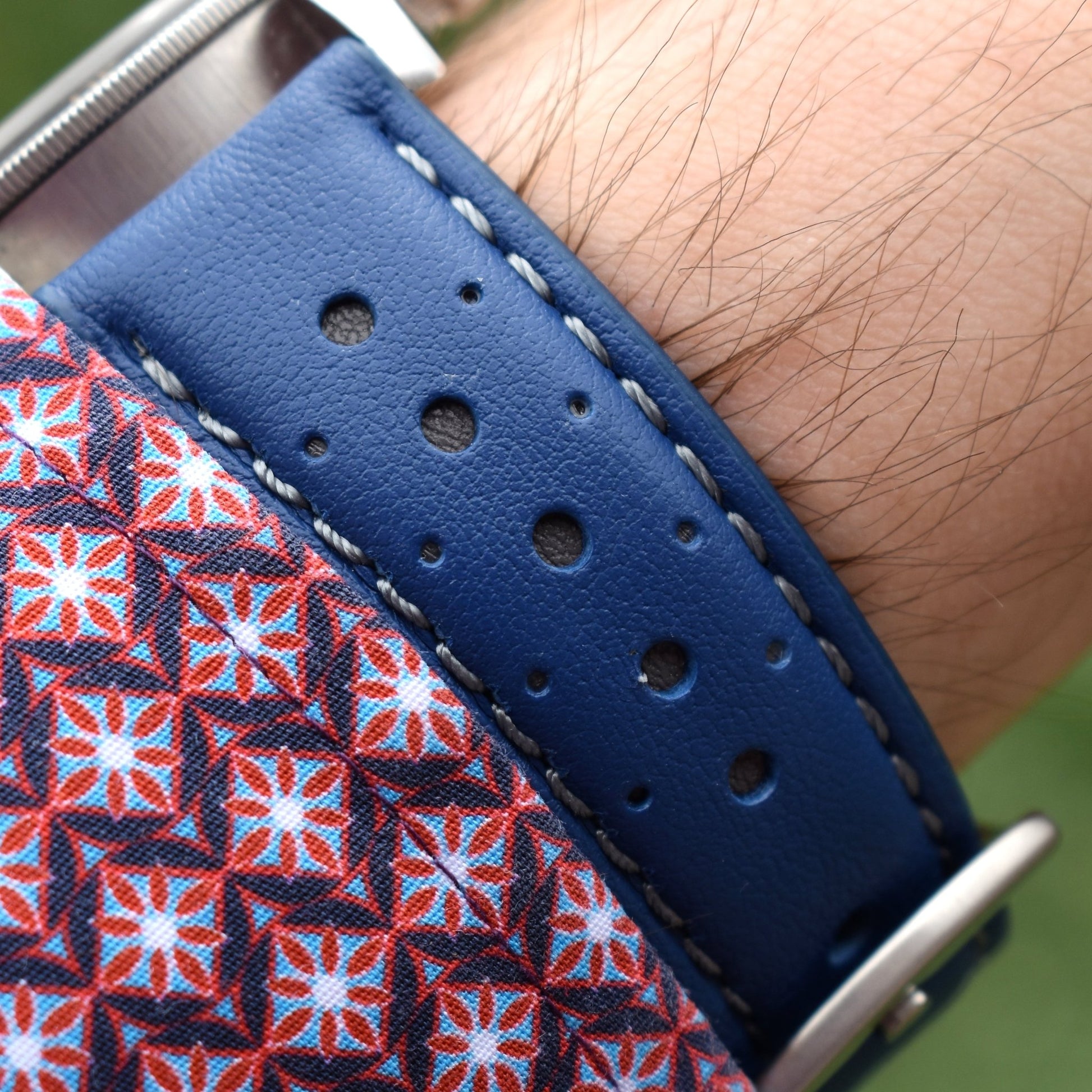 Wrist shot of the Le Mans cobalt blue and grey racing apple watch strap. Mens sleeve, grass background.