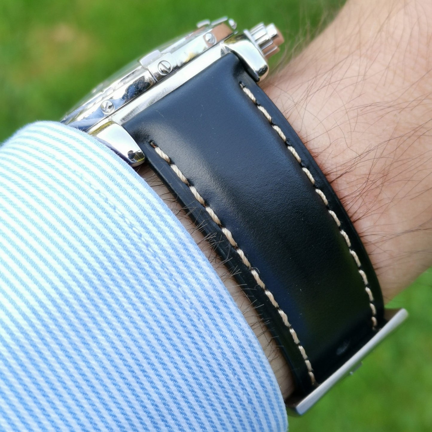 Wrist shot of the Oxford black full grain leather watch strap.  Placed on a males wrist with a blue and white sleeve.