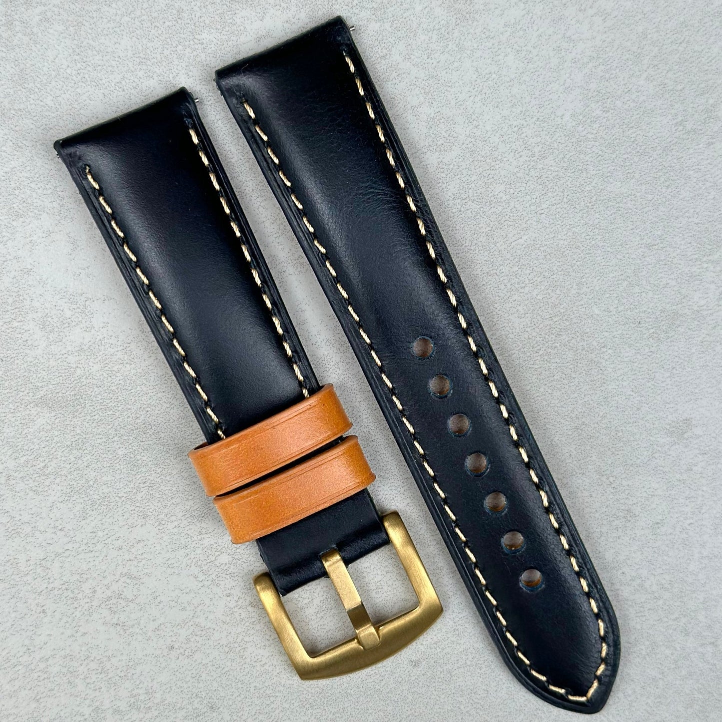 Oxford navy blue full grain leather watch strap fitted with tan loops and a PVD gold buckle.