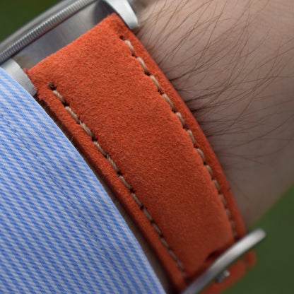 Wrist shot of the Paris orange suede apple watch strap. Padded suede strap with contrast ivory stitching.